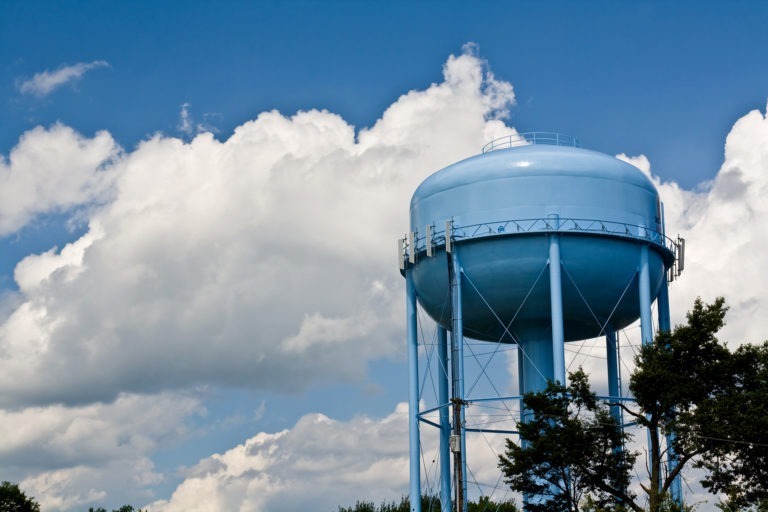 Blue water tower with cloudy sky background