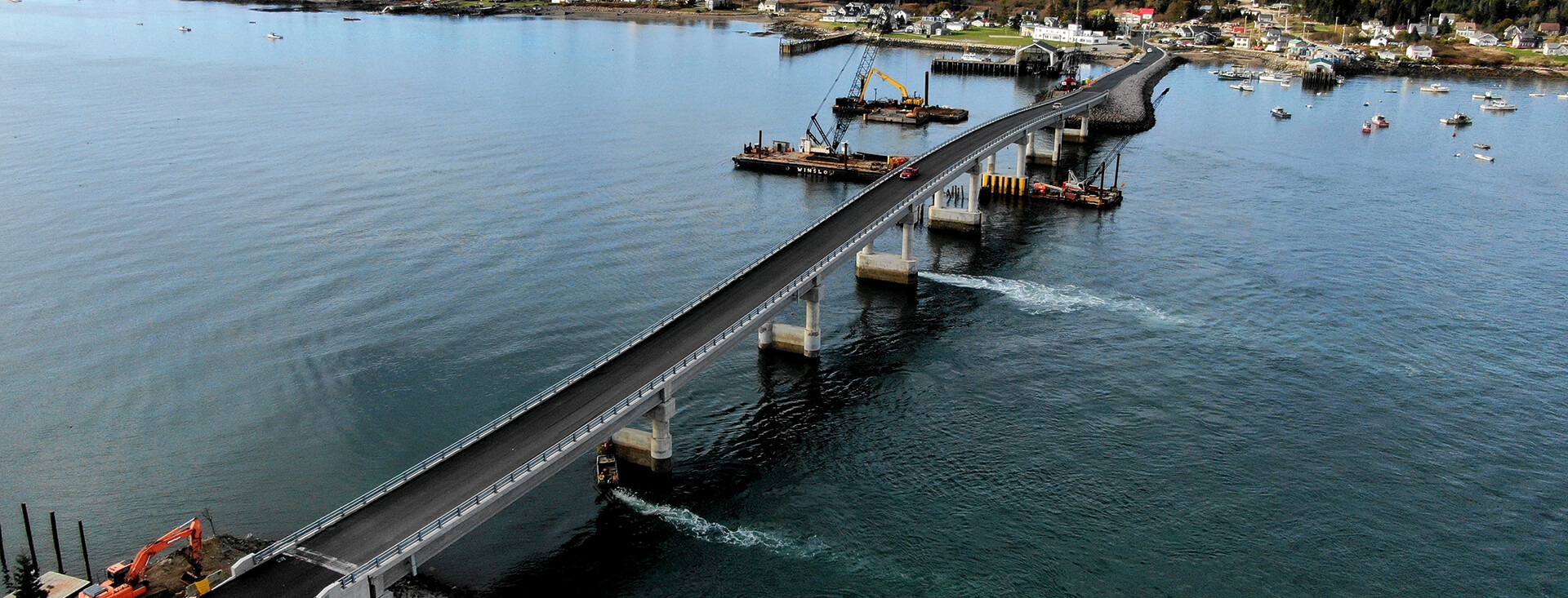 Photo of Beals Island Bridge in Maine surrounded by large mass of water, boats and industrial equipment.