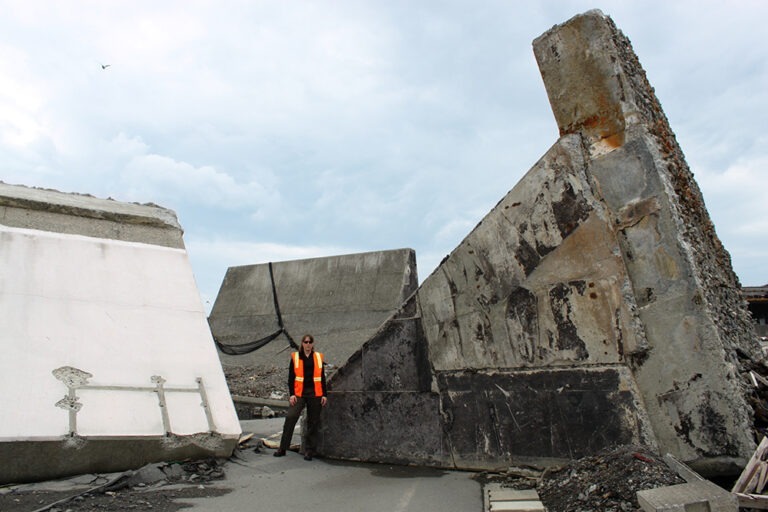 Allison Pyrch stands amid uprooted seawalls following tsunami near Fukushima, Japan.