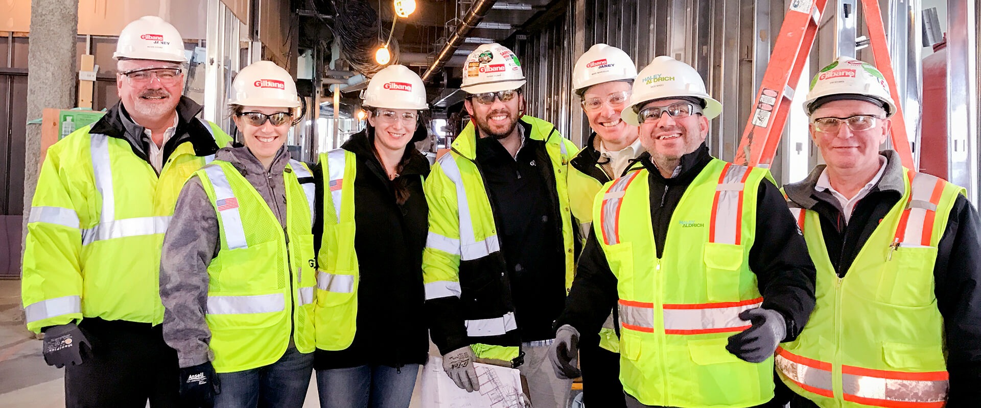 Group of men and women wearing personal protective equipment and smiling.