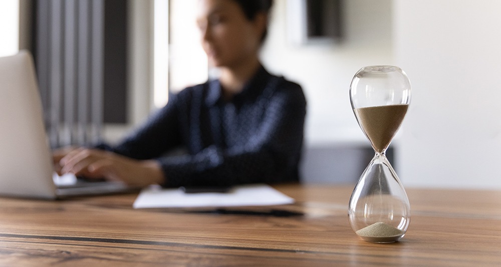 Woman typing near hourglass