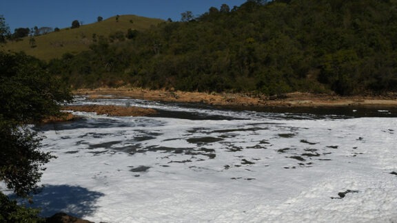 River flowing through a wooded landscape with hills in the background.