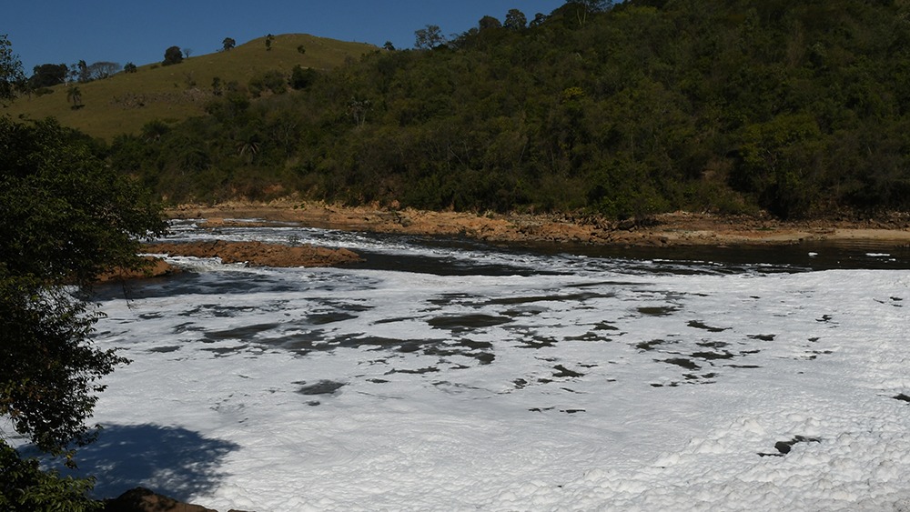 River flowing through a wooded landscape with hills in the background.